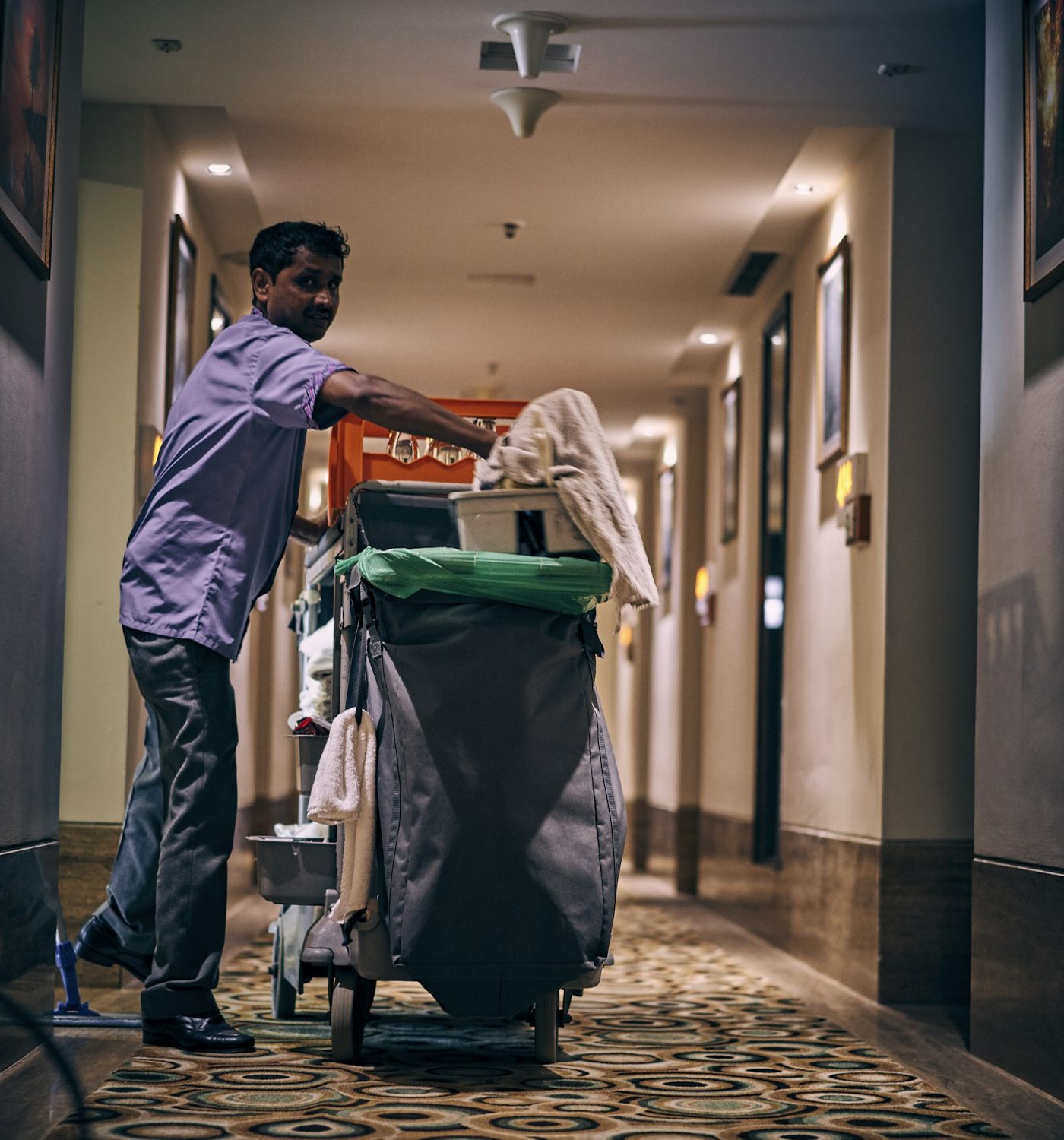 Cleaner with a housekeeping cart in a corridor